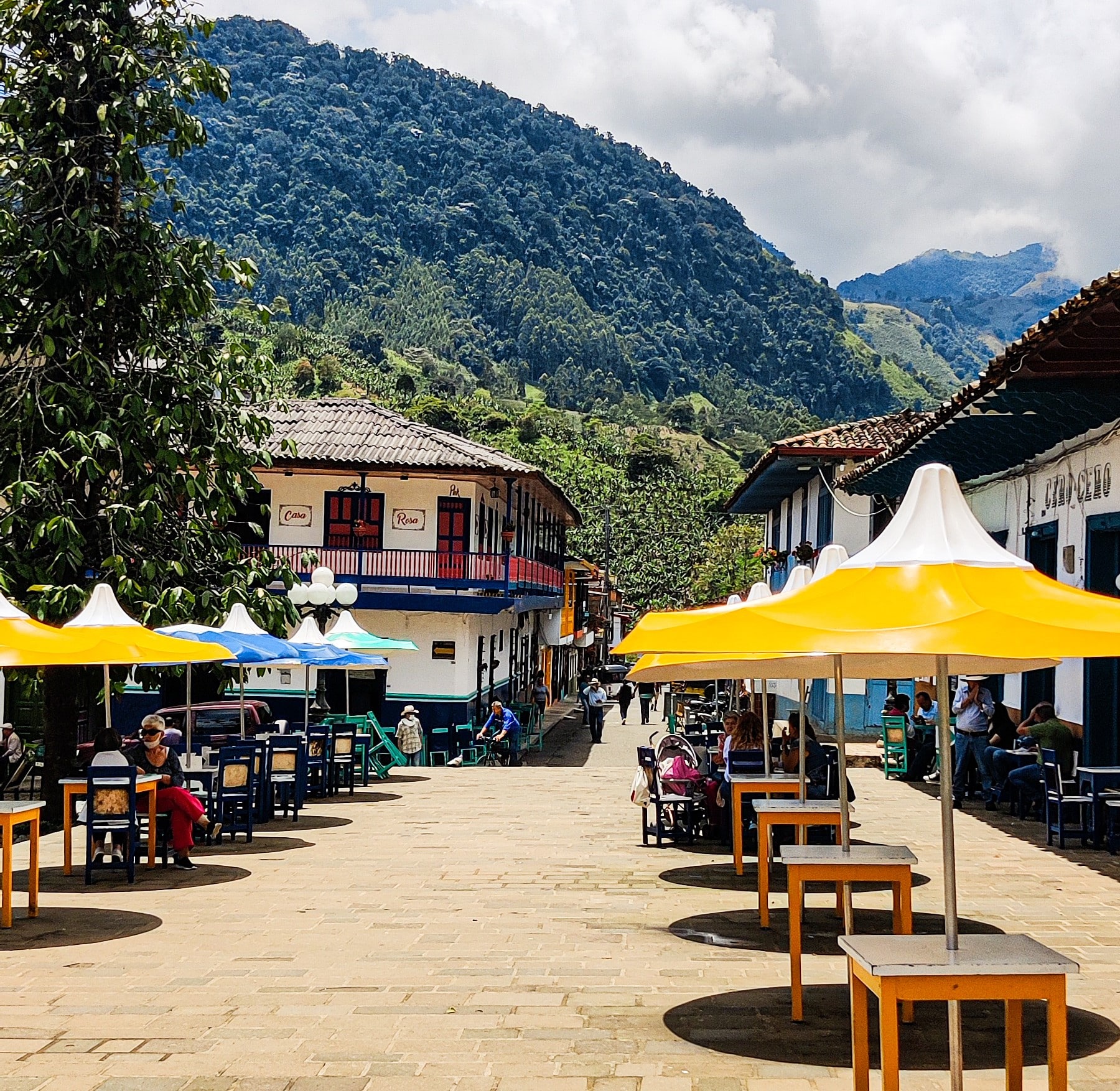 Outdoor restaurant in Jardín, Colombia, with tables set under a canopy of trees, offering a cozy and relaxed dining atmosphere.