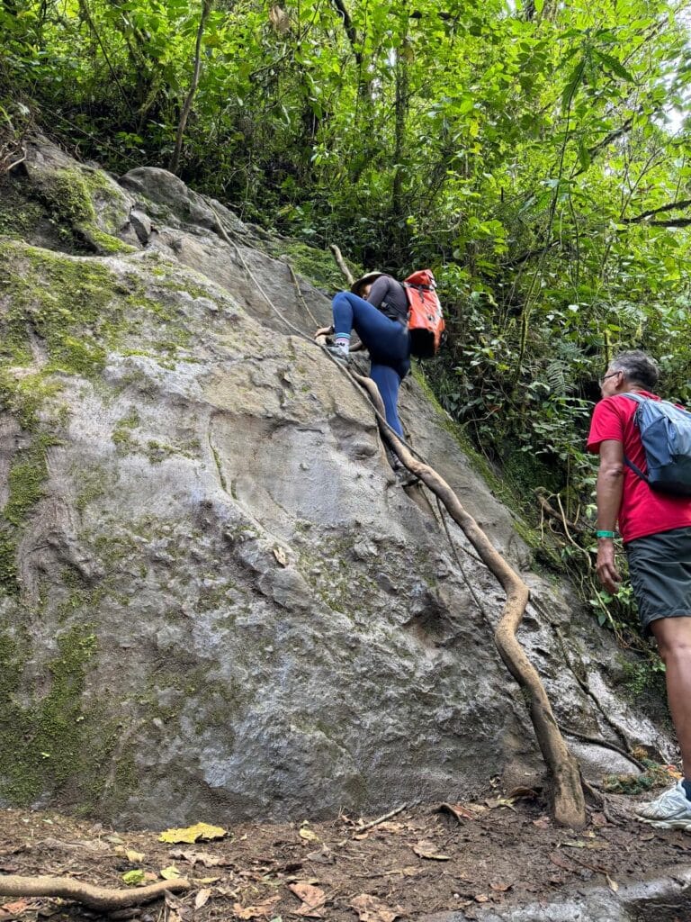 Hiker climbing a steep rocky path during the 7 Waterfalls Hike in Jardin.